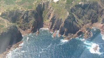 A coastal landscape with rugged cliffs and a clear view of the ocean.