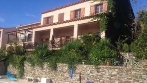 Ein Poolbereich mit Liegestühlen, einer Steinmauer und einem Gebäude mit Balkon.