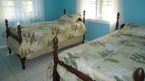 Una habitación con dos camas de madera, cada una con una colcha de estampado de hojas verdes.