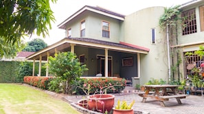 A two-story house with a covered porch, a garden with potted plants, and a picnic table.