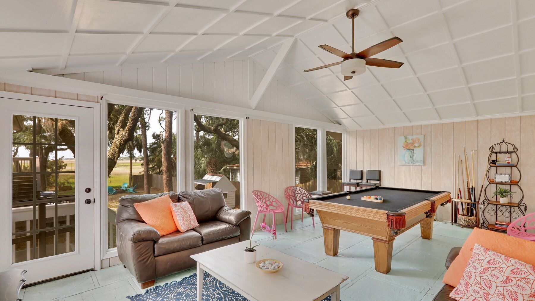 A spacious room with a pool table, a leather sofa, and a ceiling fan.