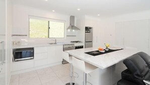Een moderne keuken met witte kastjes, een inbouwoven en een groot raam.