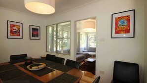 A dining area with a large table, chairs, and a window. There are framed pictures on the walls. - Carawatha | Private location in Blackheath with a rural feel (BLACKHEATH)