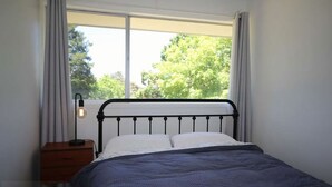 A bedroom with a bed, a nightstand, a lamp, and a window with curtains. - Carawatha | Private location in Blackheath with a rural feel (BLACKHEATH)