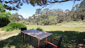 An outdoor wooden table and chairs set in a grassy area with trees in the background. - Carawatha | Private location in Blackheath with a rural feel (BLACKHEATH)