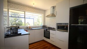 A modern kitchen with white cabinets, a black countertop, a built-in oven, a microwave, and a window providing natural light. - Carawatha | Private location in Blackheath with a rural feel (BLACKHEATH)