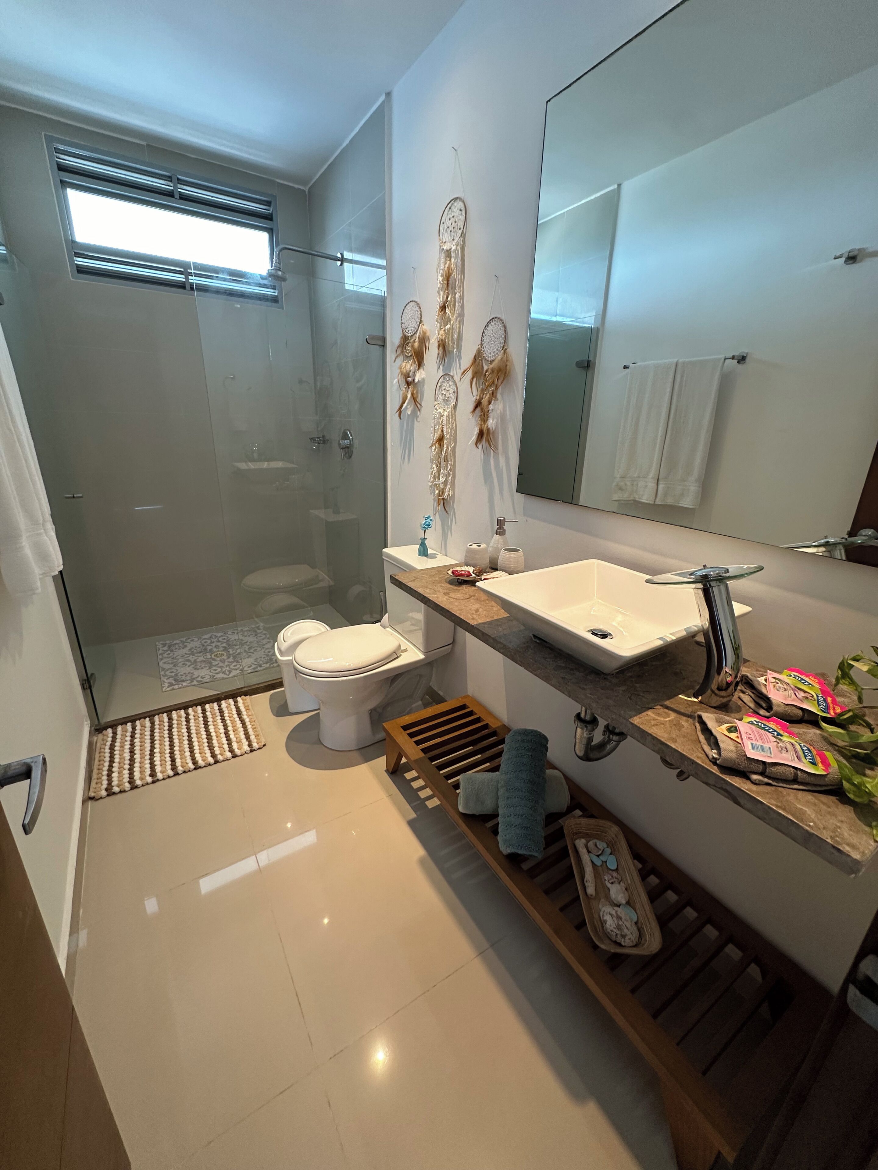 Een moderne badkamer met een douchecabine van glas, een wit toilet en een wastafel met een glazen wasbak.