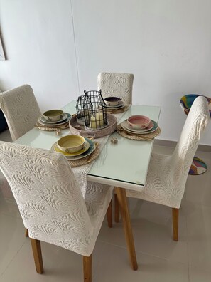 A dining table set with plates, bowls, and a candle in a room with patterned chairs and a plain wall.
