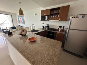 A modern kitchen with granite countertops, stainless steel appliances, and wooden cabinets. - Beachfront Apartment, Pool, Sauna, Jacuzzis, Gym. 5 Min Historical Center (Cartagena)