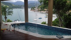 Vista des d'un balcó amb una piscina, que domina un port esportiu ple de vaixells i un paisatge de muntanyes.