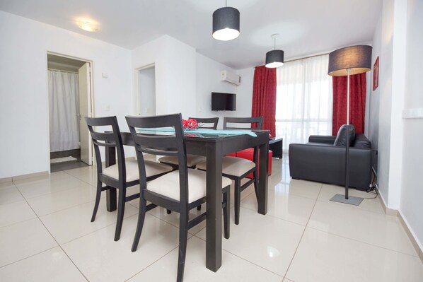A modern dining area with a rectangular table, four chairs, and two pendant lights.