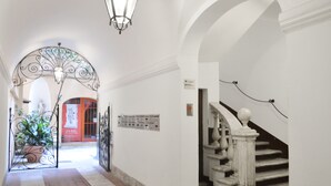 A hallway with a white staircase, a decorative metal gate, and a potted plant.