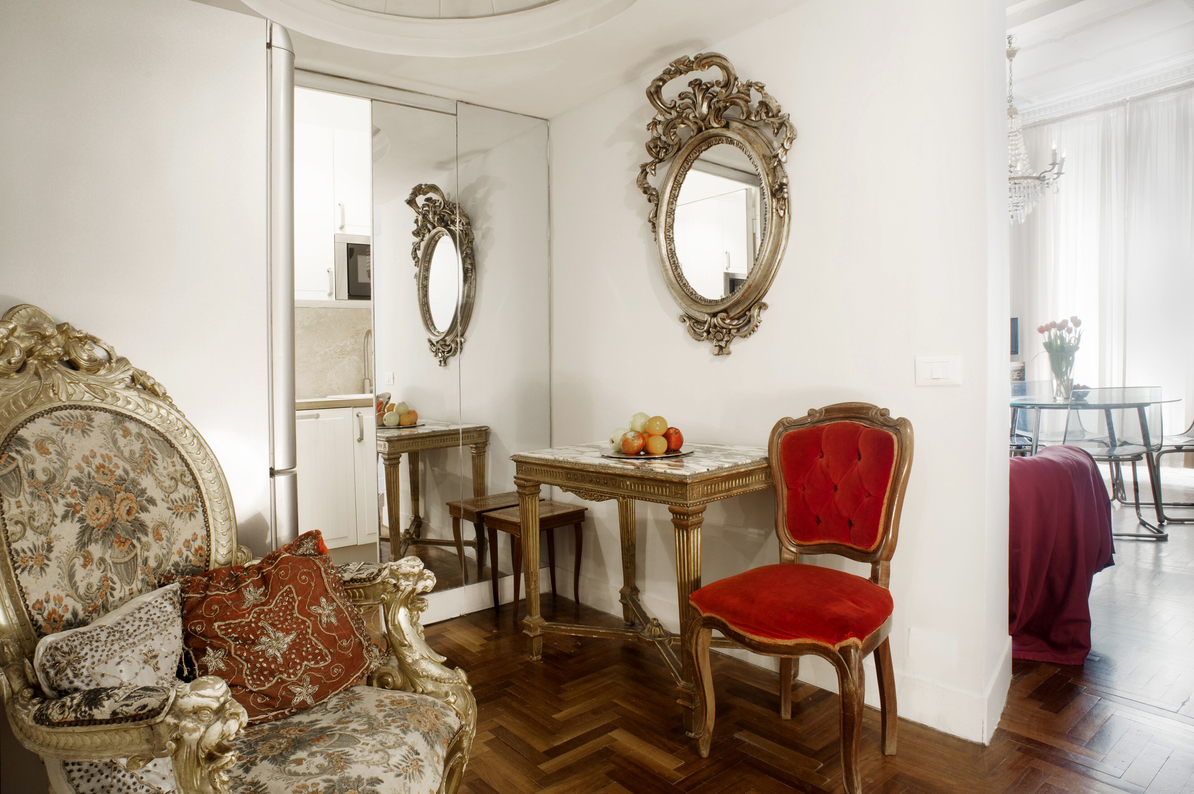 A room with ornate furniture, a mirror, and a table with fruit.