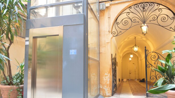 An entrance with a glass door, a metal gate, and a hallway with a light fixture.
