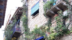 A stone building with a blue door, potted plants, and a small garden area.