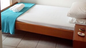 A small, single-bed room with a wooden ceiling, a window with blinds, and a bedside table with a decorative item. - A penthouse suite in Eptanisa Hotel  (Poros)