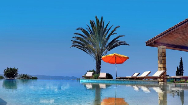 A clear pool with lounge chairs and an umbrella, surrounded by palm trees and a clear sky. - Elite, Spectacular Villa Enormous HEATED Pool Gym Excellent Location - Sleeps 15 (Argaka)