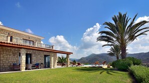 Uma villa com fachada de pedra, área de estar externa e vista para montanhas.