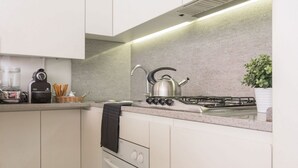Une cuisine moderne équipée d’une cuisinière à gaz, d’une bouilloire et d’un petit four.