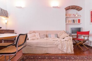A cozy living room with a sofa, a coffee table, a TV, and a bookshelf.
