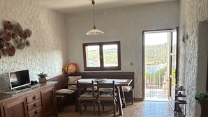 A spacious living area with a dining table, chairs, a sofa, a TV, and a window with a view. - Terrace with dreamy sunsets over the sea! ( CIN code IT111071C2000T8749) (Sant’Antioco)