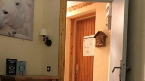 Ein gemütliches Zimmer mit einem Holzkasten, einer Lampe, einem gerahmten Bild und einer Tür zu einem weiteren Raum.