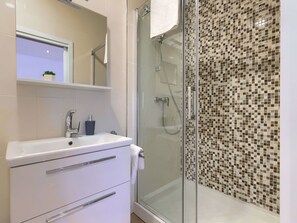 Enjoy a refreshing shower in this sleek bathroom with a glass-enclosed shower area and modern vanity.