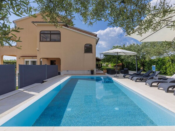 Relax by the pool surrounded by lush greenery and trees.