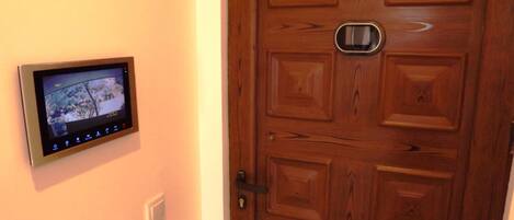 Une porte avec une caméra de surveillance fixée au mur à côté.