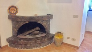 A fireplace with a stone surround, a decorative plate above it, and a vase on the floor.
