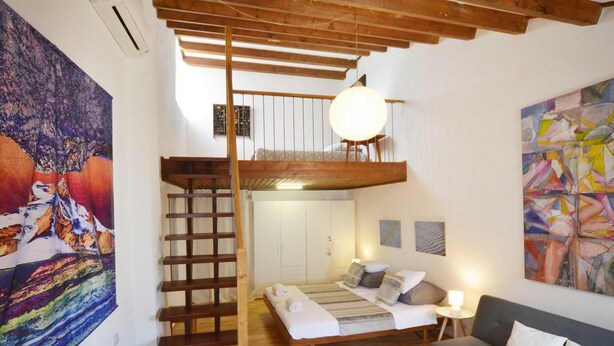 A loft-style bedroom with a wooden staircase, a bunk bed, a sofa, and a large abstract painting. - Dala Apartment in Rovinj Centre (Rovinj)