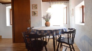 A dining area with a round table covered by a checkered tablecloth, surrounded by four chairs. There is a potted plant on the table, and the room has wooden flooring and a wooden ceiling. - Dala Apartment in Rovinj Centre (Rovinj)