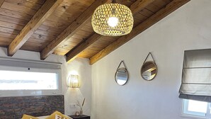 A bedroom with a bed, wooden ceiling beams, a hanging light fixture, a window with a view, and a wall-mounted mirror. - Ideal villa for relaxation, with pool and whirlpool, good views of the mountains (el roque)
