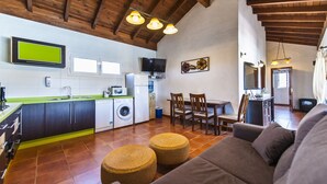 A modern kitchen with a washing machine, a dining area with wooden chairs, and a living room with a sofa and ottomans. - Ideal villa for relaxation, with pool and whirlpool, good views of the mountains (el roque)