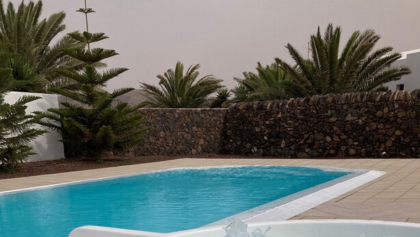 A swimming pool with a hot tub, surrounded by palm trees and a stone wall. - Ideal villa for relaxation, with pool and whirlpool, good views of the mountains (el roque)