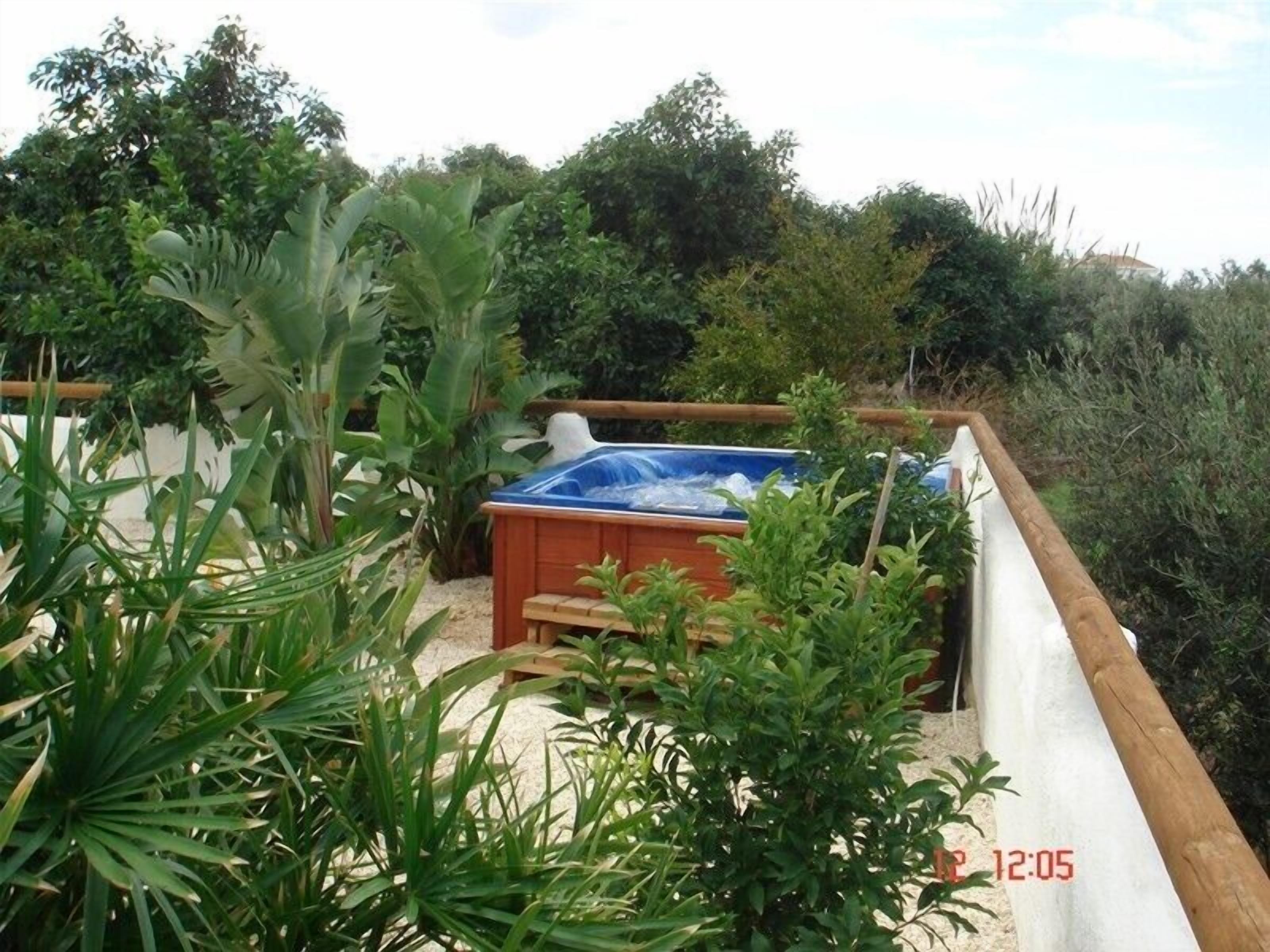A hot tub surrounded by lush greenery and a wooden deck.