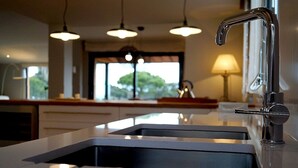 A modern kitchen with a central island, stainless steel sink, and pendant lighting. - Modern Villa (Center Of Begur) Overlooking Both Village And Sea (Begur)