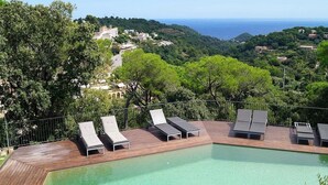 A poolside area with lounge chairs and a view of the sea and hills. - Modern Villa (Center Of Begur) Overlooking Both Village And Sea (Begur)
