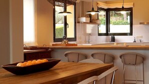 A modern kitchen with a wooden island, pendant lighting, and a view of greenery outside. - Modern Villa (Center Of Begur) Overlooking Both Village And Sea (Begur)