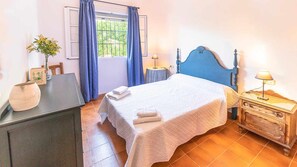 A bedroom with a bed, bedside tables, a desk, a chair, a window with curtains, and a potted plant. - Santa Ana Holiday Home in Marchena, Seville. (Marchena)