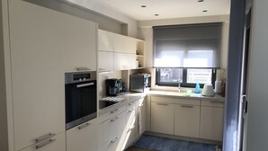 A modern kitchen with a built-in oven, a coffee maker, and a sink.