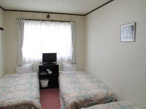 A room with two single beds, a television on a stand, a small shelf with items, and a window with curtains. - Pension Rapan (Katashina)