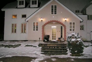 A two-story house with a central entrance, a covered porch, and a small front yard. - Pension Rapan (Katashina)