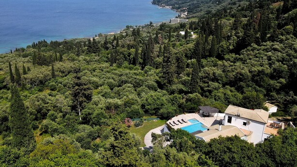 Une villa avec piscine, entourée d’une forêt dense et offrant une vue sur la côte.