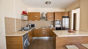 Eine moderne Küche mit Holzausstattung, einer Waschmaschine, einer Mikrowelle, einem Backofen und einem Kühlschrank.