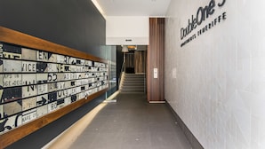 A hallway with a wall displaying various signs and a staircase leading to another area. - Doubleone3 Apartments (Teneriffe)