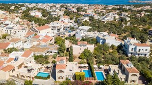 A coastal residential area with multiple houses, a swimming pool, and a view of the sea. - Family villa Elia with heated pool, 2 minutes walking to local amenities (Rethymno)