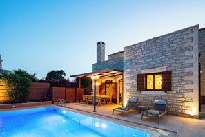 A swimming pool with lounge chairs and a covered patio area. - Family villa Elia with heated pool, 2 minutes walking to local amenities (Rethymno)