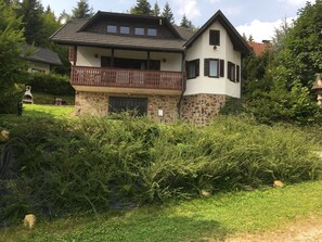 A two-story house with a stone facade, a balcony with wooden railings, and a small satellite dish on the roof. - Alpine Style House with Stunning Views, Walking, Biking, Rogla Ski Area+Spa 5km (zrece)