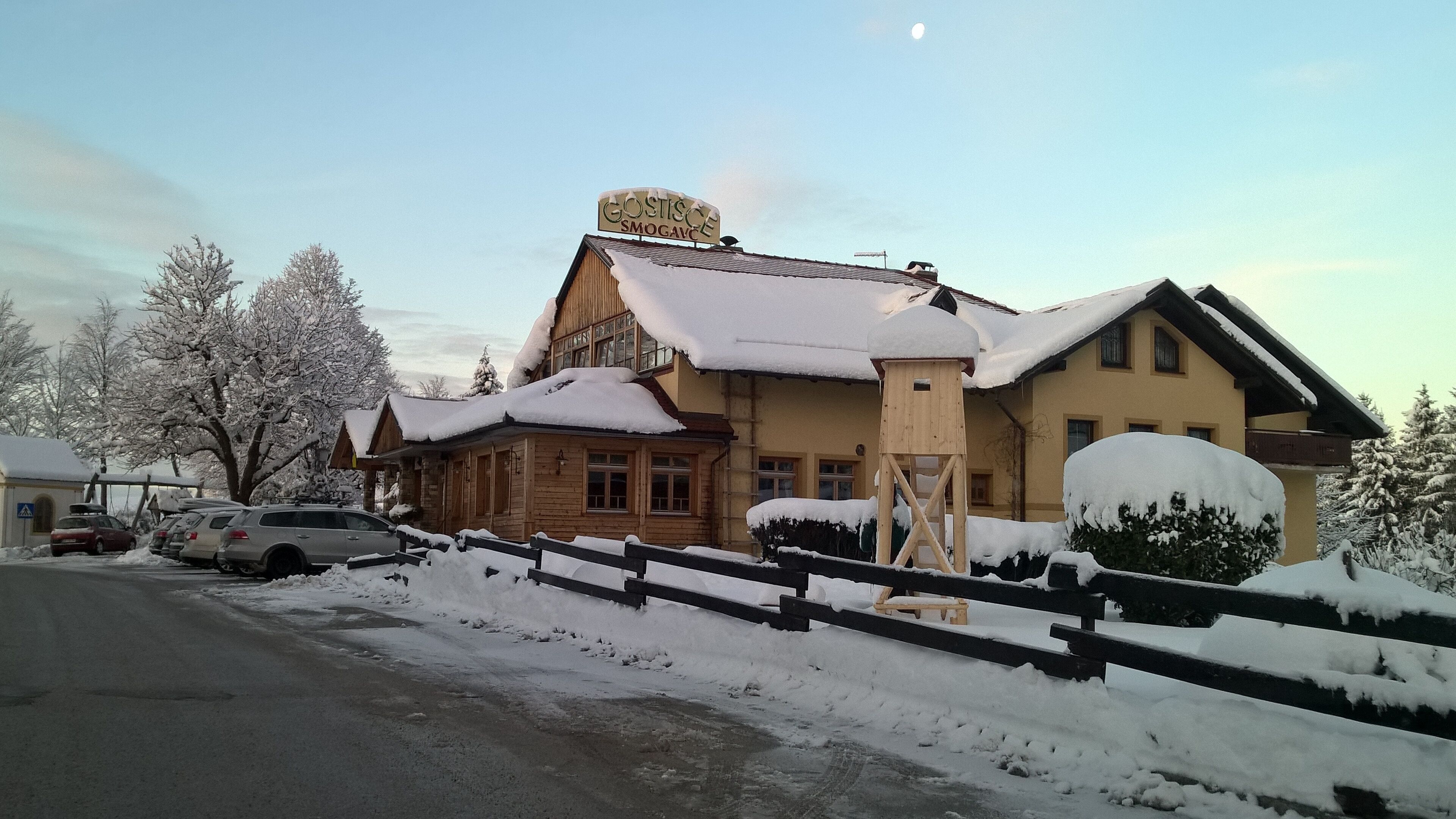 Ein Hotel mit Holzfassade, einem sichtbaren Schild und einem mit Schnee bedeckten Dach.